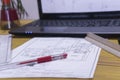 Closeup shot of blueprints on paper and on a laptop screen on office desk