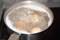 Closeup shot of boiling water with brown eggs on a stainless casserole