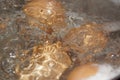 Closeup shot of boiling water with brown eggs on a stainless casserole