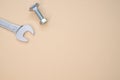 Closeup shot of bolt, nut, and an open wrench isolated on a pink background