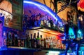 Closeup shot of bottles of spirits and liquor in a colorful bar with neon lights at night