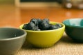 Closeup shot of a bowl of blueberries near empty bowls on a wooden surface