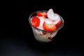 Closeup shot of a bowl of fresh strawberries with cream on a black surface Royalty Free Stock Photo