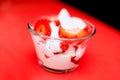 Closeup shot of a bowl of fresh strawberries with cream on a red surface Royalty Free Stock Photo