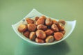 Closeup shot of a bowl of roasted chestnuts on a green surface