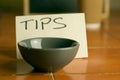 Closeup shot of a bowl with a tips note in the background on the table