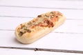 Closeup shot of a bread loaf with pizza toppings on a white table