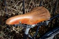 Closeup shot of a brown seat of a bicycle with dried small branches on the background