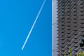 Closeup shot of a building with white plane trails in a clear blue sky in the background Royalty Free Stock Photo