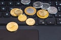 Closeup shot of a bunch of coins on the keyboard of a laptop