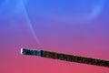 Closeup shot of a burning incense stick on pink and blue background Royalty Free Stock Photo