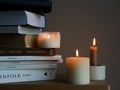 Closeup shot of candles and a stack of books on a wooden table