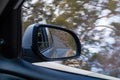 Closeup shot of car's sidemirror from inside the car while driving against blur nature background