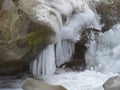 Closeup shot of a cascade of water with white ice melting on the rock