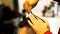 Closeup shot of a Caucasian barber cutting his client& x27;s hair.