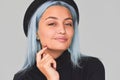 Closeup shot of cheerful and charming teenager woman with blue hair wearing black apparel and hat, smiling. Cute positive female Royalty Free Stock Photo