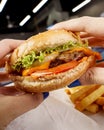 Closeup shot of the cheese burger and fries in the hands Royalty Free Stock Photo