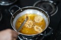 Closeup shot of chef's hand holding tongs while cooking fried calamari in a pan