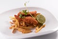 Closeup shot of chicken nuggets with french fries and lime in a white plate Royalty Free Stock Photo