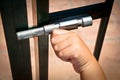 Closeup shot of a child's hand closing a silver sliding latch on a gate