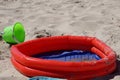 Closeup shot of a children's inflatable pool with no water and a toy bucket on the sand Royalty Free Stock Photo