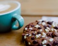 Closeup shot of a chocolate cookie and a cup of cappuccino with a blurred background Royalty Free Stock Photo