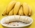 Closeup shot of chopped bananas and a bundle of ripe bananas on a yellow surface