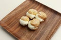 Closeup shot of choux pastry buns on a wooden plate Royalty Free Stock Photo
