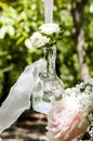 Closeup shot of a clear glass bottle hanging from a cloth with white roses inside as a decoration Royalty Free Stock Photo