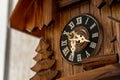 Closeup shot of a clock with Roman numbers on a wooden surface