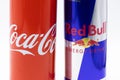 a closeup shot of a coca cola can and a redbull can next to each other on a white background