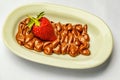 Closeup shot of cocoa cream and single red strawberry on beige plate on white surface Royalty Free Stock Photo