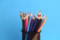 Closeup shot of colorful pencils in a metal pen holder on a blue background Royalty Free Stock Photo