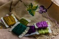 Closeup shot of colorful yarn rolls on a piece of fabric with cross-stitch art of purple grapes Royalty Free Stock Photo