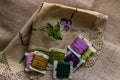 Closeup shot of colorful yarn rolls on a piece of fabric with cross-stitch art of purple grapes Royalty Free Stock Photo