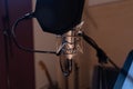 Closeup shot of a condenser microphone with a pop filter and a blurred background Royalty Free Stock Photo