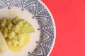 Closeup shot of the cooked Romanesco broccoli in the plate on the red surface