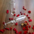 Closeup shot of a couple of glasses of champagne and red roses on a wooden table