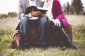 Closeup shot of a couple sitting on a suitcase while reading the bible with a blurred background Royalty Free Stock Photo