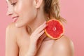 Close up shot cropped blonde half naked woman 20s perfect skin nude make up hold in hand grapefruit isolated on pastel Royalty Free Stock Photo