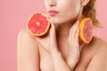 Close up shot cropped blonde half naked woman 20s perfect skin nude make up hold in hand grapefruit isolated on pastel Royalty Free Stock Photo