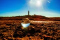 Closeup shot of a crystal ball with a lighthouse on the rocky seashore