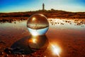 Closeup shot of a crystal ball with a lighthouse on the rocky seashore