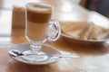 Closeup shot of a cup of Caffe macchiato next to pastries and sugar packets on a wooden surface Royalty Free Stock Photo