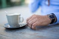 Closeup shot of a cup of coffee and a mans hand with a cigarette Royalty Free Stock Photo