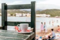 Closeup shot of a cup of coffee on a wooden table at the beach Royalty Free Stock Photo