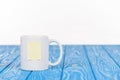 closeup shot of cup with empty note paper on wooden blue surface Royalty Free Stock Photo