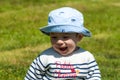 Closeup shot of a cute happy little boy in a hat sitting on a grass Royalty Free Stock Photo