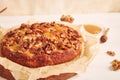 Closeup shot of a delicious apple walnut cake with honey surrounded by ingredients on a white table Royalty Free Stock Photo