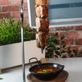 Closeup shot of a delicious barbeque hanging over a bowl of soup